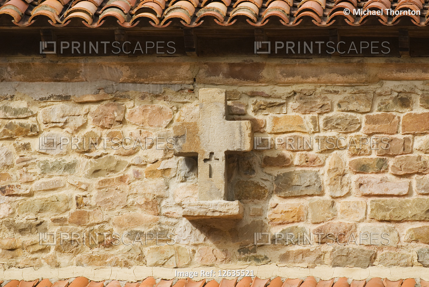 Stone cross on outer wall of the village church in Barcena Mayor, Cantabria, ...