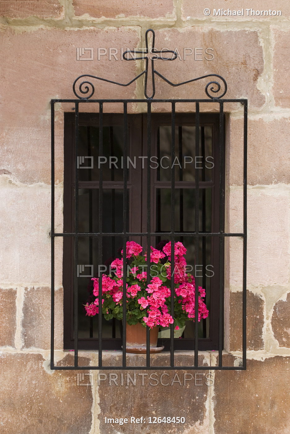 Window with flowers and religious symbol in the village of Carmona, Cantabria, ...