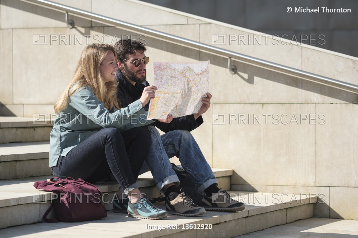 Tourists sitting on steps reading their map, Bilbao, Pais Vasco, Spain,