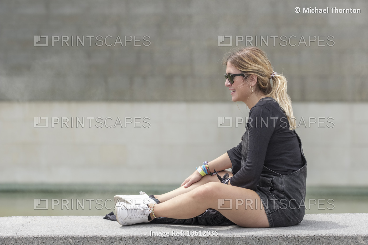 Young blonde lady with Ponytail, sitting on wall relaxing, Bilbao, Vizcaya, ...