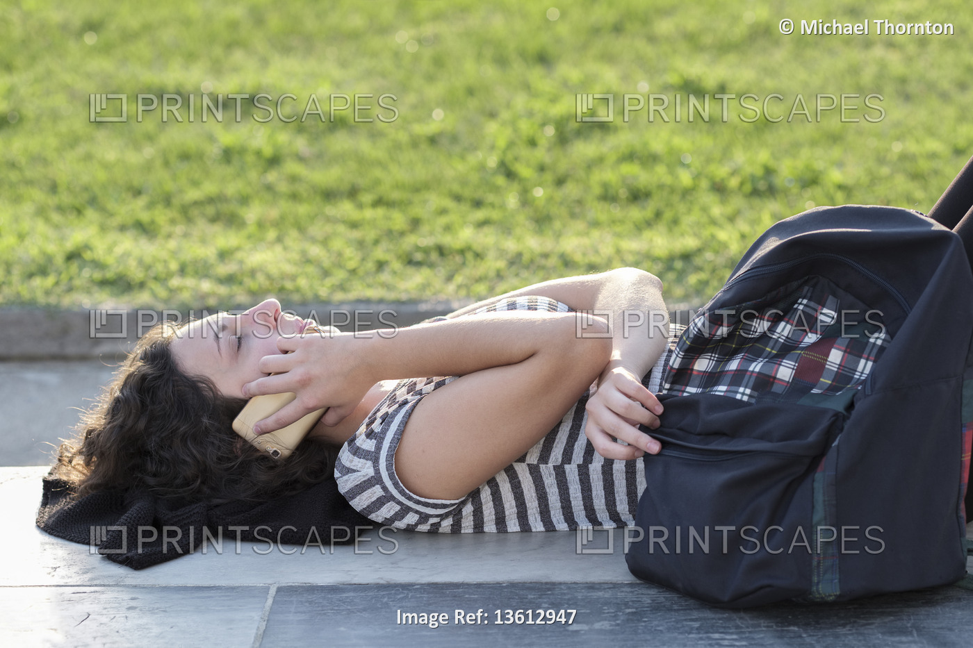 Young lady on mobile phone lying down in the Piazza dei Miracoli, Pisa, ...