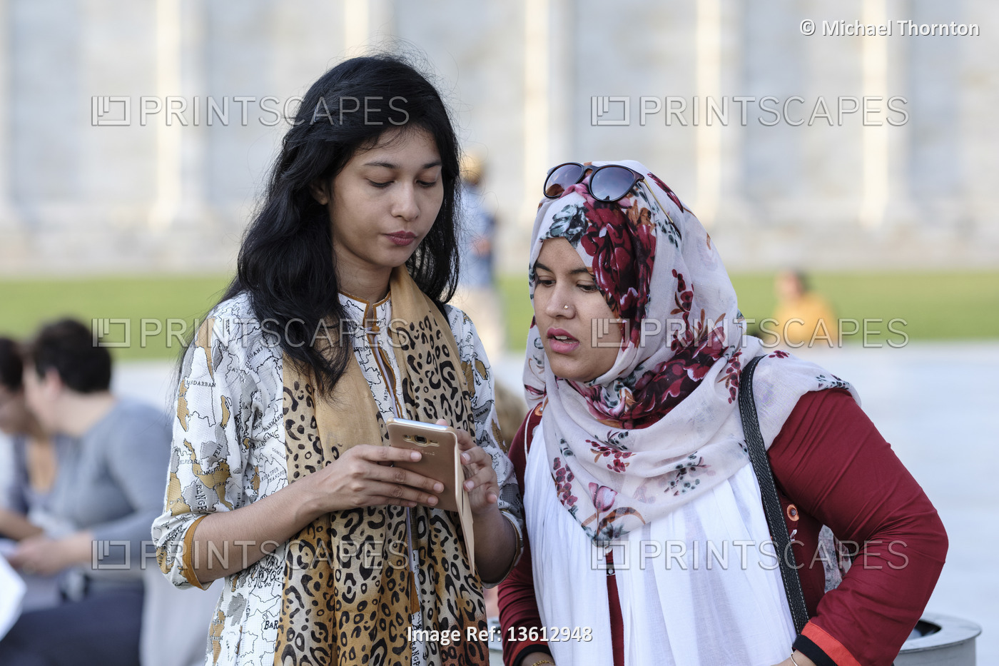 Two ladies using mobile phone in the Piazza dei Miracoli, Pisa, Tuscany, Italy, ...