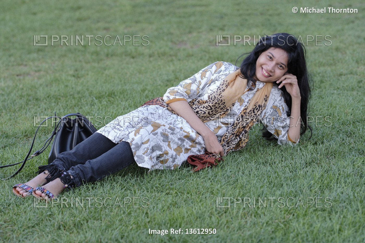 Young lady from Bangladash lying down on grass in the Piazza dei Miracoli, ...