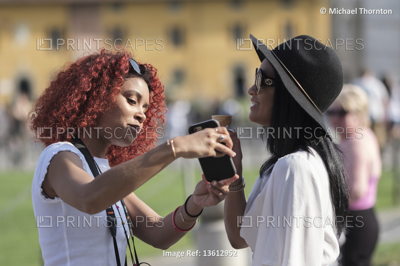 Two young ladies comparing smartphone images at the leaning tower of Pisa, Pisa ...