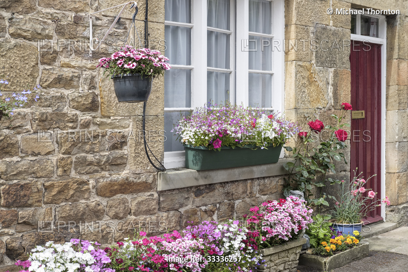Old cottage doorway with baskets of assorted flowers